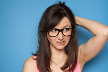 Young confused woman on blue background