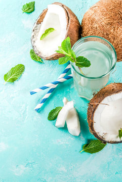 Healthy food concept.  Fresh Organic Coconut Water with coconuts, ice cubes and mint, on light blue background, copy space top view