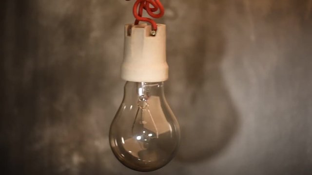 Rocking light bulb on electric cable dark room