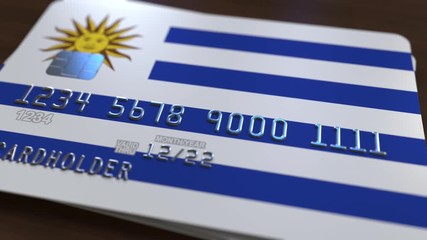 Plastic bank card featuring flag of Uruguay. National banking system related animation - Powered by Adobe