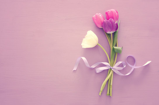 bouquet of pink and white tulips over pastel wooden background. Top view.