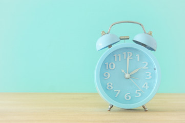 Image of spring Time Change. Summer back concept. Vintage alarm Clock over wooden table.