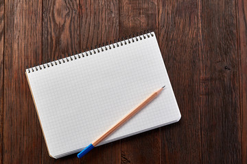 White checked copybook with pencil on pine brown wooden board