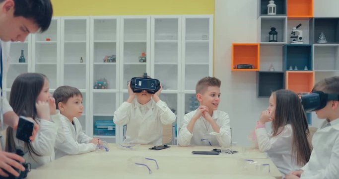 Schoolgirl and schoolboy in the classroom watching in virtual reality glasses