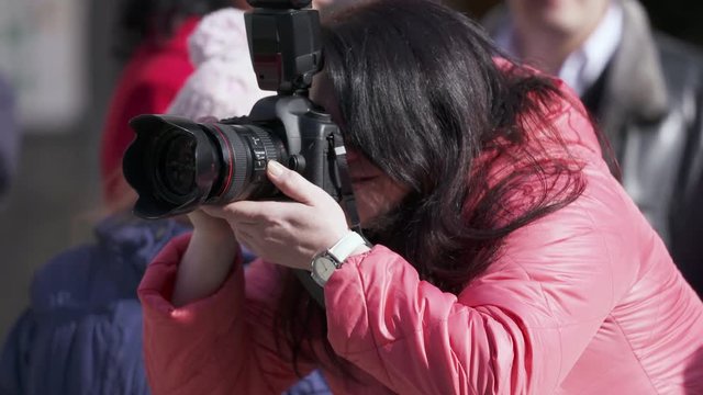 Professional woman photographer with digital camera taking a picture at an outdoor event. Closeup, shallow depth of field.