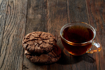 Cup of tea with cookies on a cutting board on a wooden background, top view