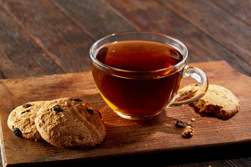 Cup of tea with cookies on a cutting board on a wooden background, top view