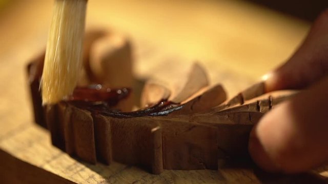 Extreme closeup view of male master doing carpentry on furniture manufacture, and covering wooden piece with varnish slow motion