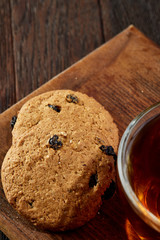 Cup of tea with cookies on a cutting board on a wooden background, top view