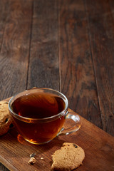 Cup of tea with cookies on a cutting board on a wooden background, top view