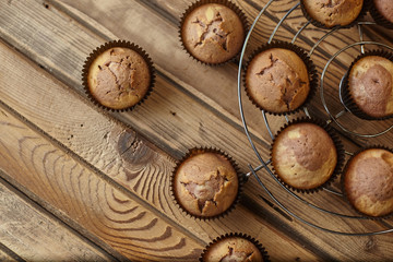 Fototapeta na wymiar Cupcakes in brown paper form on an iron stand on a wooden table