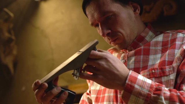 Portrait of concentrated involved in work man doing carpentry on handmade wood manufacture, and checking out his creation slow motion
