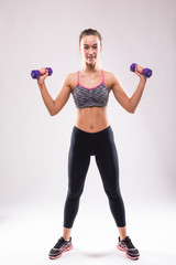 Portrait of young happy smiling woman in sportswear, doing fitness exercise with dumbbells over white background
