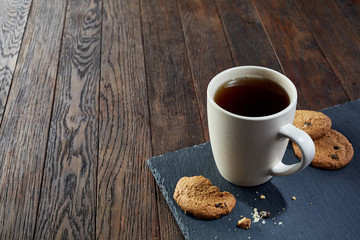 Cup of tea with cookies, workbook and a pencil on a wooden background, top view