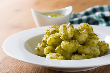 Gnocchi with pesto sauce in plate on wooden table