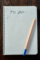 Cup of tea with cookies, workbook and a pencil on a wooden background, top view