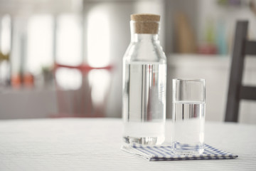Water bottle and glass of water on kitchen table - Powered by Adobe