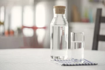 Zelfklevend Fotobehang Water bottle and glass of water on kitchen table © sebra