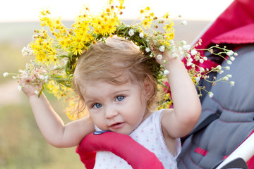 pretty smiling little girl with a wreath on her head close-up