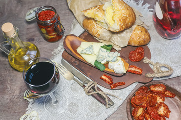 A glass of dry red wine and Italian Focaccia bread with cheese and a cheese platter with figs and Gorgonzola, brie, DorBlu and grapes. Selective focus.