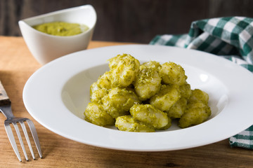 Gnocchi with pesto sauce in plate on wooden table