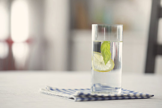 Glass of water with lemon and mint in kitchen