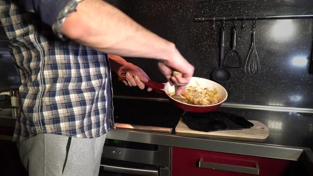 a man puts cooked food out of a frying pan into a plate
