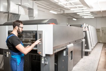 Printing operator working with offset machine at the printing manufacturing