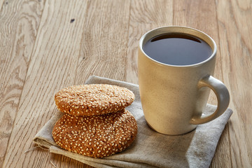 Porcelain teacup with chocolate chips cookies on cotton napkin on a rustic wooden background, top view