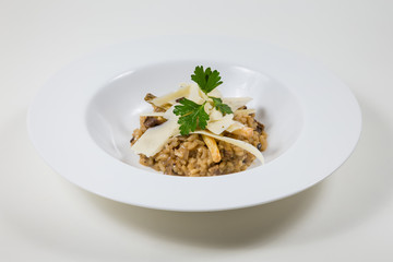 Mushroom risotto with parmesan in a white bowl on a white background isolated