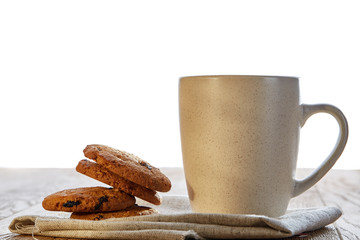Porcelain teacup with chocolate chips cookies on cotton napkin on a rustic wooden background, top view