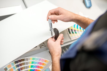 Man measuring thickness of the paper sheet with micrometer at the printing plant