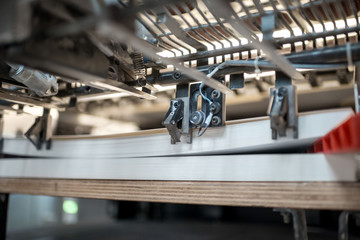 Fragment of the offset printing machine during the printing at the manufacturing