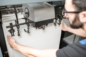 Worker filling up the paper sheets for printing into the offset printing machine at the manufacturing