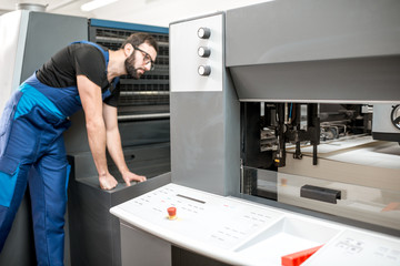Worker following a printing process on the offset machine at the manufacturing
