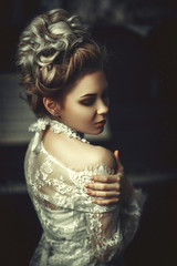 Beautiful model wearing white lace dress is posing in an interior studio 