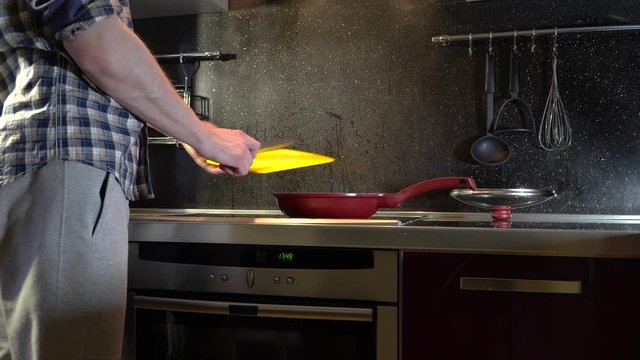 a man throws sausage from a cutting board into a frying pan
