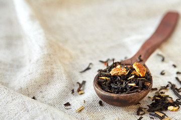Closeup of a wooden spoon filled with scattered tea leaves, shallow depth of field, top view