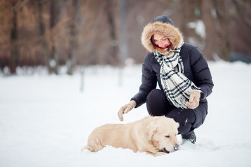 Picture of woman squatting next to labrador in winter park