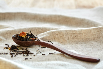 Closeup of a wooden spoon filled with scattered tea leaves, shallow depth of field, top view