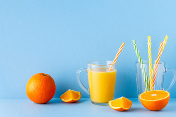 Fototapeta na wymiar Orange juice on a blue pastel background