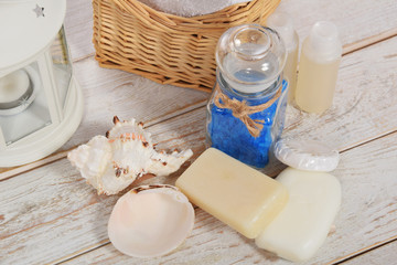 Fototapeta na wymiar wicker basket with towel and sponge mini shampoo mini soap and sea salt with scallop with free space for text