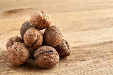 A stack of walnuts piled together and on rustic wooden background, shallow depth of field, selective focus