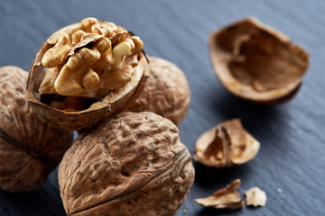 Top view close-up shot of cracked walnuts on dark background, shallow depth of field, macro
