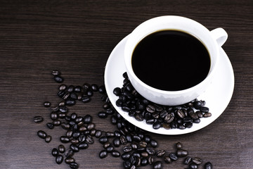 Black coffee in cup and coffee bean on wood background.