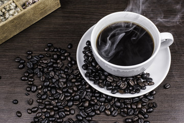 Black coffee in cup and coffee bean and box on wood background.