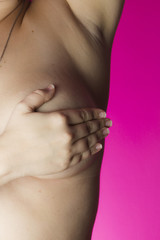 Woman with hands on breasts on a pink background / Outubro Rosa
