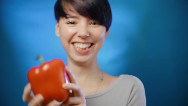young girl holds a red pepper and dances