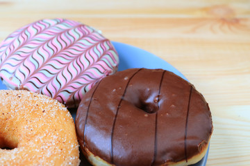 Three types of tasty doughnuts served on wooden table with selective focus and blurred background 