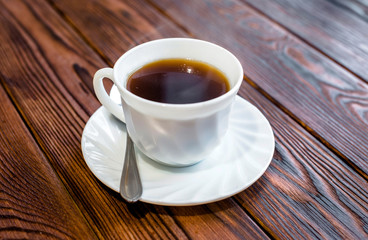 A cup of hot coffee stands on a wooden table 